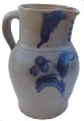 S399 Cobalt-Decorated Stoneware Pitcher,Baltimore, MD origin, circa 1875, ovoid-bodied pitcher with tooled rim and applied strap handle, decorated with a brushed cobalt flower extending from a groups of leaves.   brushwork flanking the spout.   chips to the base Stoneware pitcher Baltimore , Peter Hermann