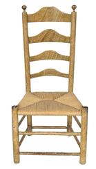 K295 Early 19th century original mustard grain painted Ladder Back Chair featuring curved slats in the back, turned finials on posts and tightly woven rush seat. Measurements:  18 ¾ wide x 39 tall. The seat is 15 ½ tall.  