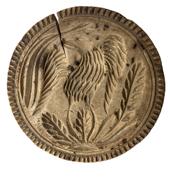 K1650 19th century Pennsylvania butter print stamp depicting a deeply chip-carved Eagle with leaves. A decorative edge encircles the outer edge of the stamp.  Surface cracks from age. Dry, natural patina surface. Measurements: 5 diameter x 3 tall. 