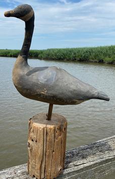 F299 Decoy, Goose, by John Albert Lundgren,On the bottom of the goose, stenciled in black paint:" PAT. SEPT 23, 1941 Straw stuffed goose decoy. Canvas body with white and black painting. Wire loop extending from tail to hang up the goose. Square metal bracket on bottom of the goose used to attach it to a stake. Patent number on bottom of the goose. .