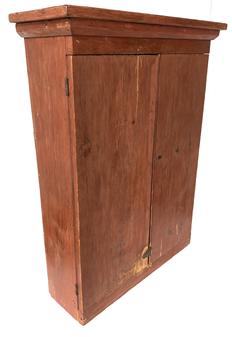 G405 19th century Pennsylvania Hanging Cupboard in the original dry red paint, two panel doors with applied molding, the interior has two shelves which are mortised into the sides, wide back board held in place with square head nails. Top measurements are: 27 ¼ wide x 9 deep. Case measurements are: 24 ½ wide x 7 ¾ deep.  