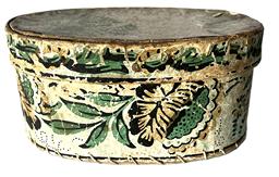 K253 19th century Pennsylvania small oval wallpaper Hat Box or Bandbox.  The outside of the oval pasteboard box is covered in wallpaper bearing a floral pattern in greens, reds, black, browns and pale blues. The interior and bottom of this box is uncovered.  Measurements: 7 wide x 5 deep x 3 ¼ tall.  