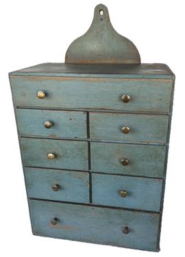 **SOLD** K1733 Exceptional early 19th century Pennsylvania eight drawer apothecary with decorative shaped cut out back bearing the most beautiful original blue painted surface. Unusual layout features graduated drawers in a one-over-four-over-one configuration. Dovetail drawers with square head nail construction case. Hole in back for hanging but also sits level and displays nicely on a flat surface. Circa 1820s. This is one of the best hanging apothecaries we have had in a long while! Measurements: 15 wide x 9 ¼ deep x 26 tall (back center) x 19 ½ tall (front).  