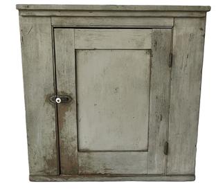 K175 19th century Pennsylvania small hanging corner cupboard bearing original gray painted surface and applied molding along the top. Mortised and pegged door opens to reveal a white painted interior with shelf for added storage. Square head nail construction. The wood is pine.  Circa 1860s-1880s.  Measurements:  27 tall and takes a 19 corner.  