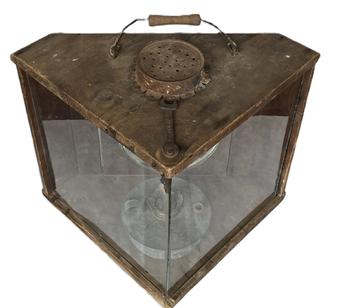 **SOLD** H76 Early 20th century triangular shaped wooden gunning light / lantern with glass front panels. A punched tin can is attached over the top hole to protect the flame from wind / rain. Original wire bale handle with wooden grip remains intact on top for carrying purposes. Old Ford wrench attached to screw on top of front to adjust tension securing the glass panels in place. Hinged door on back for access to internal burner and reflector. Retains wonderful natural patina weathered surface. We purchased this amazing lantern from the DuPont Estate  however the stamp on the side of lantern indicates it was originally from the R.H. Richardson Collection of Cambridge, Maryland. Measurements: 15 ½ wide x 16 deep x 14 tall. 