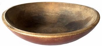 Late 18th century wooden bowl in beautiful worn, dry original red paint. Hand turned out of round with wide band around the top. Very unique flattened edge on opposite sides of the top opening that appear to have been created/used for propping the bowl steadily on its edge to scrape contents from inside the bowl. Natural patina interior reflects wear chop marks and cracks indicative of age and use. Out of round at 16 1/2" X 17 1/4 " diameter x 5 deep.