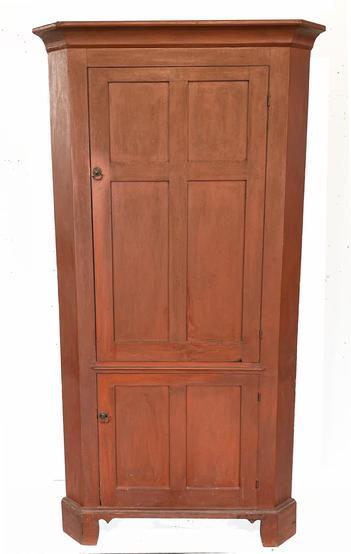 H1037 Late 18th century  early 19th century Pennsylvania original red painted corner cupboard with a tall, four panel door over a smaller, two panel door configuration. Doors are fully mortised and feature beaded edges. Top doors open to reveal decoratively shaped / butterfly shelves painted a  white