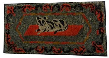 Y217 An outstanding example of American folk art, This  hooked rug patterns of the later 19th century, and it was probably hooked sometime around 1890. This rug features a princely Tabby cat on a red rug, A floral garland surrounds the cat, Strips of wool cloth were used for the hooking and it was done on burlap.The rug measures 19 1/2 x 37 3/4