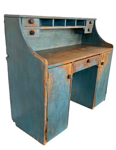 K274 Unusual 19th century Pennsylvania Merchant's Desk with unique hidden hinged drop-down writing surface in old blue painted surface. Desk boasts drawers and pigeonholes in the top section for added storage. The top board is hinged so that it can be raised to utilize the top row pigeonholes for sorting taller items. The lower section, known as a kneehole style, boasts two doors and a center drawer.  This versatile piece could be used against a wall  or it could be shared by two parties simultaneously as a Partners Desk. Wire nailed construction. Circa 1870s. Measurements:  47 ¼ wide x 20 deep x 41 ¾ tall (back) x 2/ ½ tall (front).  