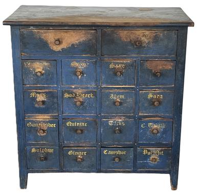 **SOLD** K100 Fantastic early 19th century New England Apothecary boasting spectacular early blue painted surface with 18 dovetailed drawers bearing original hand carved knobs and remnants of hand painted yellow labels. Unusual configuration with 2 drawers over 16 drawer layout. The drawer stretchers are double mortised into the case. The ends are post and panel construction. The wood is all white pine.  Circa 1820s. Measurements: 34 wide x 19 deep x 34 ½ tall.