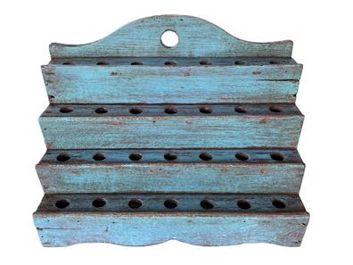 **SOLD** K1660 Rare early 19th century four-tiered Pipe drying Rack boasting a shaped back, and a decorative scalloped apron along the front. Rack retains original old blue painted surface. Each tier has seven holes for drying pipes near the hearth. Rack retains a hole for hanging purposes in the tall, cut out back  or it can sit level on a flat surface. The wood is pine, with small square head and wire nail construction. NOTE: Sharing pipes was a common practice of the times. Once clay pipes were shared in Taverns or Inns, the stem tips were snapped off and the pipes were washed and dried in preparation for the next user. This tiered configuration, multi-hole style rack was used for drying the freshly washed, various length pipes by the hearth. Measurements: 14 ¾ wide x 8 deep x 11 tall (back).  