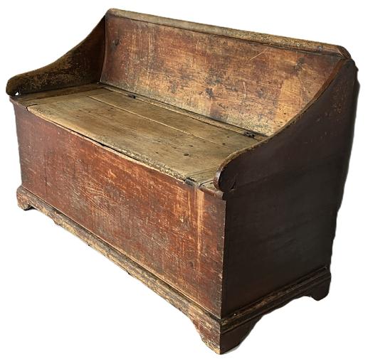 **SOLD** K1826 Early Pennsylvania Settle / Wood Box circa 1800-1820, in the original dry red painted surface with a dovetailed case, single lift lid with applied breadboard ends, lollipop shaped ends and arched back resting on applied bracket base. The wood is pine. Measurements: 47 ½ wide x 20 ½ deep x 29 tall.  