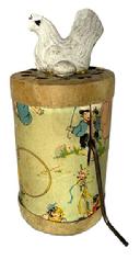 M30 Early 20th century cardboard and tin litho �Clucking Hen� toy � designed to produce a cackling sound when the metal handle is wound. A chalkware figure of a chicken with egg adorns the top, while the litho covering the cylinder depicts children at play with hoops, balloons, roller skates and a May Pole. The original label markings remain on bottom � indicating Made in U.S.A. � Patented 1936 � The Cackling Hen � Dist. By AY-WON TOY NOV. CORP. N.Y.C. The cackling sound works well when handle is turned. Some wear and tear by handle from use.  2 &frac14;� diameter x ~4 &frac34;� tall. 