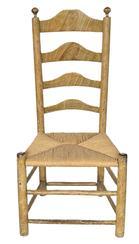 K295 Early 19th century original mustard grain painted Ladder Back Chair featuring curved slats in the back, turned finials on posts and tightly woven rush seat. Measurements:  18 &frac34;� wide x 39� tall. The seat is 15 &frac12;� tall.  