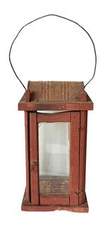M320 Pennsylvania wooden Lantern featuring four glass panels contained within a wooden post construction frame retaining an old red painted surface.  Tiny wire loop hinges allow the door to open freely for access to the interior. There is a hole in the top for ventilation purposes and the make-do hood that protects the internal flame from wind/rain is created with part of an old metal can. A wire bail handle is attached to the top for carrying/hanging purposes. Measurement: 5 &frac12;� square x 10 &frac14;� tall at corner posts. Overall height is approximately 15 &frac12;� tall including handle in upright position. 