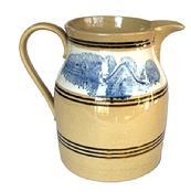 **SOLD** L295 Exceptional and very attractive Mocha decorated yellow ware pitcher with multiple black bands.  Dating to the 1800s, this was molded and decorated by master potters and is of the highest quality. The very crisp mocha decoration is blue seaweed on a white background. Several decorative black bands adorn the pitcher both above, and below the mocha decorations. Measurements: 6� bottom diameter x 8� tall.  