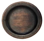 **SOLD** M21 Wooden plate with remnants of red paint on the bottom and dark, natural patina interior. Plate boasts a wide lipped edge and rests on an ever so slightly raised foot. Both sides of this plate show evidence of use. Out of round. Measurements ~ 7 &frac12;� x 7 &frac34;� diameter x ~3/4�-~1� tall, depending on where measured. The lipped edge is &frac34;� wide. 