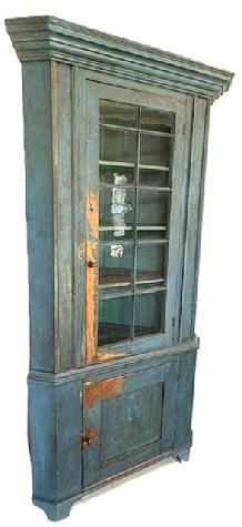 M51 Early 19th century Centre County, Pennsylvania corner cupboard bearing the original blue painted surface. Two-piece construction with one door with 10 windowlites with outstanding wavy, bubbled glass, over a single panel door below resting on a nice cut out base. Beaded edges surround each of the fully mortised and pegged doors. The molded window muntins are also mortised through the door frame. Beautiful, wide cornice molding around top, applied molding along both sides of the front and at waist. The interior retains original blue painted surface and boasts shelves in both sections for added storage. Plate grooves in upper shelves. Wide boards on back. The wood is pine with primarily square head nail construction. Circa 1800 � 1820s. Measurements: 88� (7� 4�) tall. Takes a 33 &frac12;� corner at top molding. Case tales a 28� corner. 
