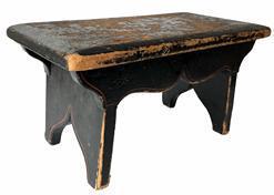 J152 Pennsylvania paint decorated wooden foot stool retaining original black painted surface with remnants of floral paint decoration on the top and simple pinstriping accents on the apron and each of the slightly splayed legs. The drop aprons on each side are mortised into the legs and boast a nice cut out that matches the cut out on each leg/foot. Chamfered edges along the top show extensive wear indicative of years of use. Square head nail construction. Circa 1840-1850�s.  Measurements: 15 &frac34;� wide x 8 &frac14;� deep x 8� tall
