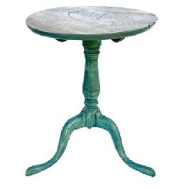 L438 Late 18th Century New England Candle Stand in original blue painted surface circa 1760 -1790 with a very beautiful turned center column resting on three padded feet that are dovetailed into the column. The one board top is secured by early wooden pegs to which is attached to the base. Wonderful, early, iron blacksmith made brace is added to secure legs, which is nicely done. The wood is walnut. The candle stand is all original. Measurements: 19 1/4" x 19 1/2" top diameter x 24" tall. 