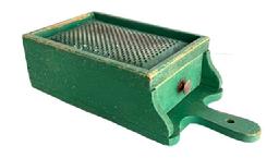 RM1630 Early wooden box grater with drawer retaining its original dry green painted surface. Grater boasts a hand punched perforated, heavy metal grater surface over a sturdy full length functional drawer that slides in and out without problems and has a small knob for easy opening/closing. A cut-out handle  with hole for hanging purposes and shaped ends by the drawer opening add to the visual appeal to this functional kitchen necessity. Maker attached a 5/8� wide strip of wood across the back to slightly elevate the upper end of the grater when in use. Great wear indicative of age and use. The wood is pine � with small wire nail construction. Circa 1880s � 1900. Measurements:15 5/8� long x7 1/8� wide x 4� tall.