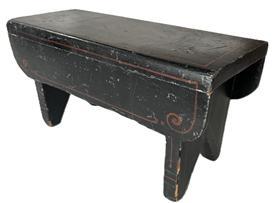 K1823 Pennsylvania paint decorated wooden foot stool retaining black painted surface with heart decoration on the top and simple red, blue and green pinstriping accents on the aprons and each of the legs and feet. The drop aprons on each side boast nicely rounded corners and pinstripe decoration. Bootjack cut out feet. The wood is pine. Square head nail construction. Circa 1840-1850�s. Measurements: 13� long x 5 &frac12;� wide x 6 5/8� tall. 