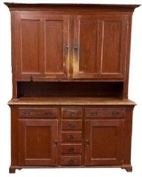 L166 Unique late-18th century to early 19th century Lancaster County, Pennsylvania original red painted two-piece stepback cupboard boasting an unusual configuration resting on an applied dovetailed bracket base with decorative cut out feet. The layout of the top consists of two fully mortised and pegged split panel doors that open to reveal shelves with plate grooves and a spoon rack along the shelf fronts. The layout of the lower part of the cupboard consists of two dovetailed drawers over two panel doors with five smaller dovetailed drawers in the center.  Cupboard is dovetailed and mortised and pegged construction with �T� nails and square head nails. Circa 1780 � 1810. Measurements: 58 &frac12;� wide (at waist) x 21� deep x 82 &frac12;� tall.  
