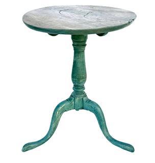 L438 Late 18th Century New England Candle Stand in original blue painted surface circa 1760 -1790 with a very beautiful turned center column resting on three padded feet that are dovetailed into the column. The one board top is secured by early wooden pegs to which is attached to the base. Wonderful, early, iron blacksmith made brace is added to secure legs, which is nicely done. The wood is walnut. The candle stand is all original. Measurements: 19 1/4" x 19 1/2" top diameter x 24" tall. 