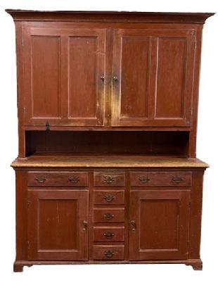 L166 Unique late-18th century to early 19th century Lancaster County, Pennsylvania original red painted two-piece stepback cupboard boasting an unusual configuration resting on an applied dovetailed bracket base with decorative cut out feet. The layout of the top consists of two fully mortised and pegged split panel doors that open to reveal shelves with plate grooves and a spoon rack along the shelf fronts. The layout of the lower part of the cupboard consists of two dovetailed drawers over two panel doors with five smaller dovetailed drawers in the center.  Cupboard is dovetailed and mortised and pegged construction with �T� nails and square head nails. Circa 1780 � 1810. Measurements: 58 &frac12;� wide (at waist) x 21� deep x 82 &frac12;� tall.   