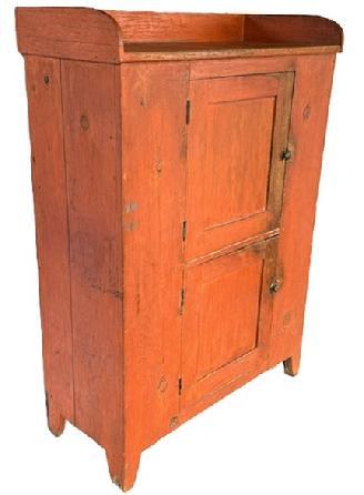 **SOLD** L131 Beautiful early 19th century Pennsylvania original bittersweet red painted jelly / storage cupboard featuring an unusual door over door configuration with applied dovetailed gallery, resting on cut out feet. The panel doors are mortised and wooden pegged construction. Case is square head nail construction. Clean, natural patina interior with shelving for added storage options. The wood is pine. Circa 1830s. Measurements: 41 &frac34;� wide x 18 &frac34;� deep x 58 &frac34;� tall (back) x 54 &frac34;� tall (front). 