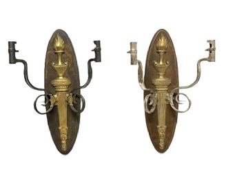 RM1647 Pair of hanging wall sconces featuring a brass flaming torch motif mounted on an oval wooden backplate with each of the candle arms constructed of bent and curled, �US� marked Bayonets. One of the sconces features two bayonets with nickel plated surfaces (~11 &frac12;� wide) and the other features two bayonets with blued surfaces (~12 &frac14;� wide). The locking ends of the bayonets, meant to attach to rifles, becoming the candle sockets for the sconces. Backs measure ~5 &frac14;� wide x ~19� tall. 