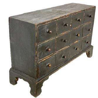 **SOLD** L406 19th century New England 12 drawer Apothecary in original Windsor green paint with dovetailed case and drawers, resting on an applied bracket base with decoratively cut out feet. The wood is pine with small wire nail and dovetail construction. Circa 1840s. Measurements: 34 &frac12;� wide x 10 &frac12;� deep (top) x 11 &frac12;� deep (base) x 22� tall.  