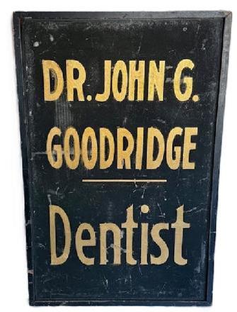 K1866 Single sided wooden Trade Sign that reads: "Dr. John G. Goodridge - Dentist". The lettering is hand painted in gold gild on a black sand-painted background with applied black painted molding surrounding all sides. Circa 1900. Measurements: 23 &frac34;� wide x 1 &frac12;� thick x 36 &frac14;� tall. 