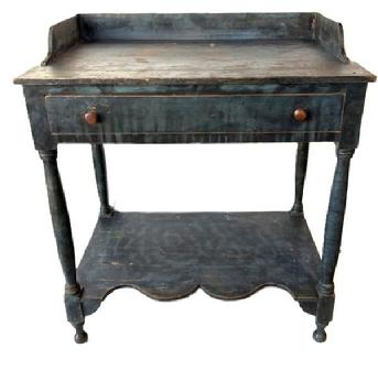 M94 Early 19th century New England Sheraton blue paint decorated open Washstand bearing original blue painted surface with black smoke decoration. Features an applied dovetailed gallery with shaped ends, a full-sized dovetailed drawer, a shelf below with a decorative shaped front edge and turned legs. All original. Square head nail construction. Circa 1820�s-1840�s
