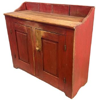 M92 Mid-19th century Pennsylvania Bucket Cupboard featuring two raised panel doors that are fully mortised and pegged � retaining old dry, red painted surface. Unusual, shallow depth with solid ends and a clean, natural patina interior. The wood is pine with square head nail construction. All original hardware and knobs. Circa 1820s-1840s. Measurements: 40� wide x 14 &frac12;� deep x 31� tall (front) x 35� tall (back).  