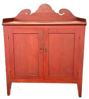 M25 Early 19th century original red painted Pennsylvania Server with applied dovetailed gallery featuring a tall, decoratively cut out backsplash with applied molding across the front of the top. Both doors are fully mortised and open to reveal a very clean, natural patina interior. The chamfered cut to the edges of legs give the appealing visual appearance of being splayed legs with the 8 &frac14;� clearance below. Circa 1800 � 1820s. The wood is pine, with square head nail construction. Measurements: 41 &frac14;� wide x 24 &frac14;� deep x 50 &frac12;� tall (center of back).  