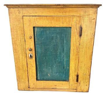L240 Small 19th century hanging cupboard boasting original mustard painted surface with original blue painted panel door. Applied molding surrounds the top. The case is dovetailed, and the door is fully mortised and wooden pegged construction. The internal shelf is mortised into the sides. The wood is pine. Circa 1850s. Measurements: 19� wide x 9 &frac14;� deep x 20 &frac12;� tall.   
