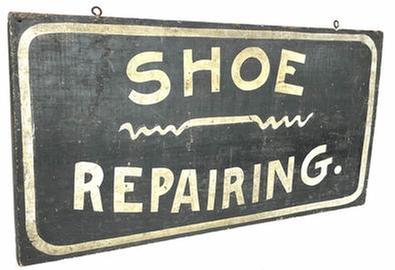 H942 Late 19th century Pennsylvania hand painted wooden Trade Sign advertising "Shoe Repairing." White painted lettering, on a single board with a white border and a shoestring design in the center on a black background. Single sided.