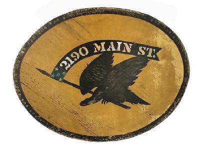K1834 Double sided wooden sign with an Eagle holding a flag/banner in its beak that reads �2190 Main Street�. Painted in black with polychrome accents on a mustard yellow colored background. Black border detail around the outside edges adds nice appeal. Old eye hooks remain intact on top and wire has been added for hanging purposes. Weathered surfaces indicate years of use in an outdoor setting. Measurements: 21 &frac12;� wide x &frac34;� thick x 17 &frac14;� tall. 