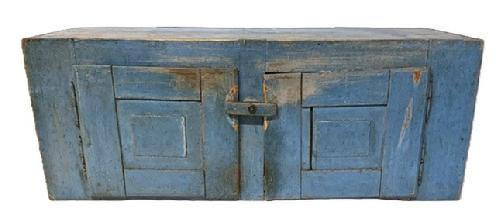 **SOLD** M267 19th century hanging cupboard bearing two raised panel doors and original blue painted surface. The wood is pine with two fully mortised raised panel doors, and dovetailed case with square head and small wire nail construction. Original turn knob secures the doors closed. Natural patina interior. Removeable shelf (later addition) inside the left door, whereas the right contains an open interior. From an Estate in Chambersburg, PA. Measurements: 44 &frac12;� wide x 16� deep x 17� tall.  