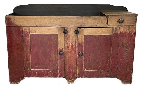 **SOLD** K1723 19th century Pennsylvania original red painted drysink with remnants of blue paint inside the well. One dovetailed drawer. Two doors below the well open to reveal shelf for additional storage. Very unusual long form with center foot to help support the weight. The wood is pine. Great wear on front from years of use. Circa 1850s. Measurements: 60� wide x 21� deep x 35 &frac14;� tall (back)